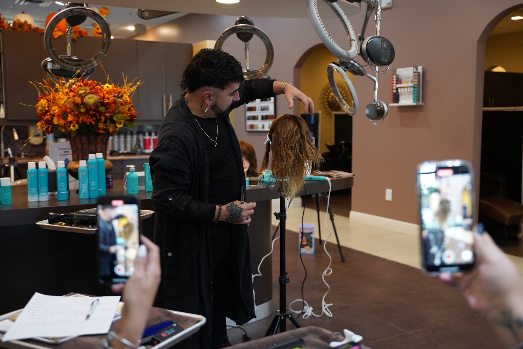 Ariel Cubas teaching a salon class, demonstrating on a mannequin while students film