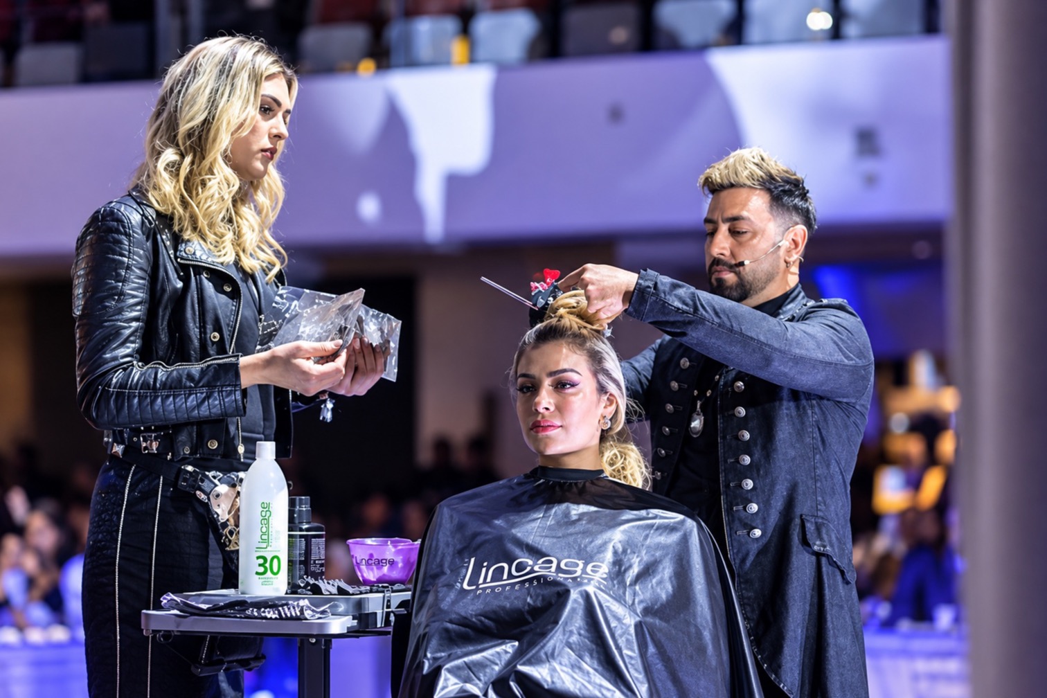Ariel Cubas working colour on a model at a hair show, assistant holding foils beside him