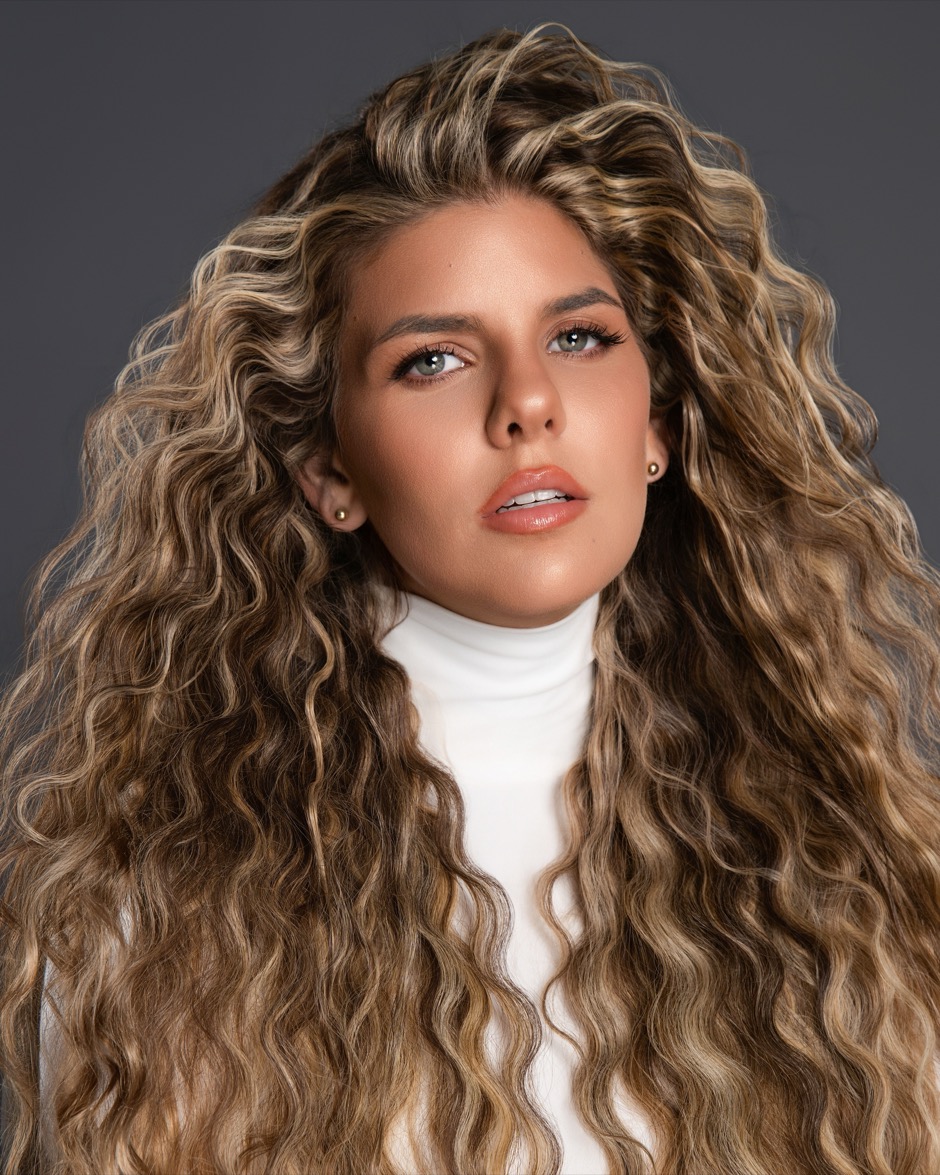 Model with long curly blonde hair and volume after shaping