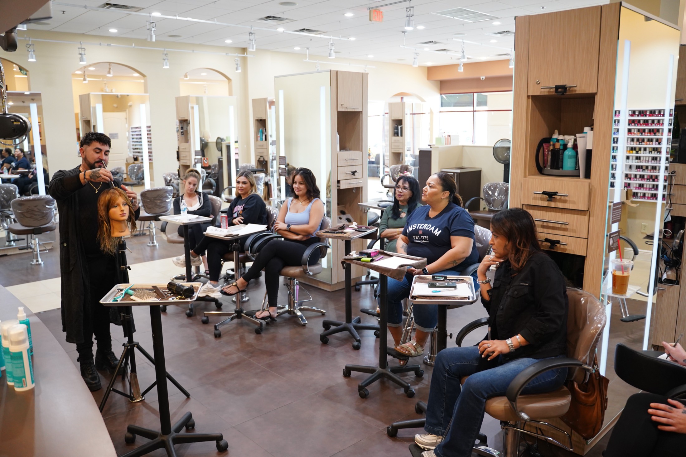 Ariel Cubas teaching a class, demonstrating on a mannequin in front of a group of stylists