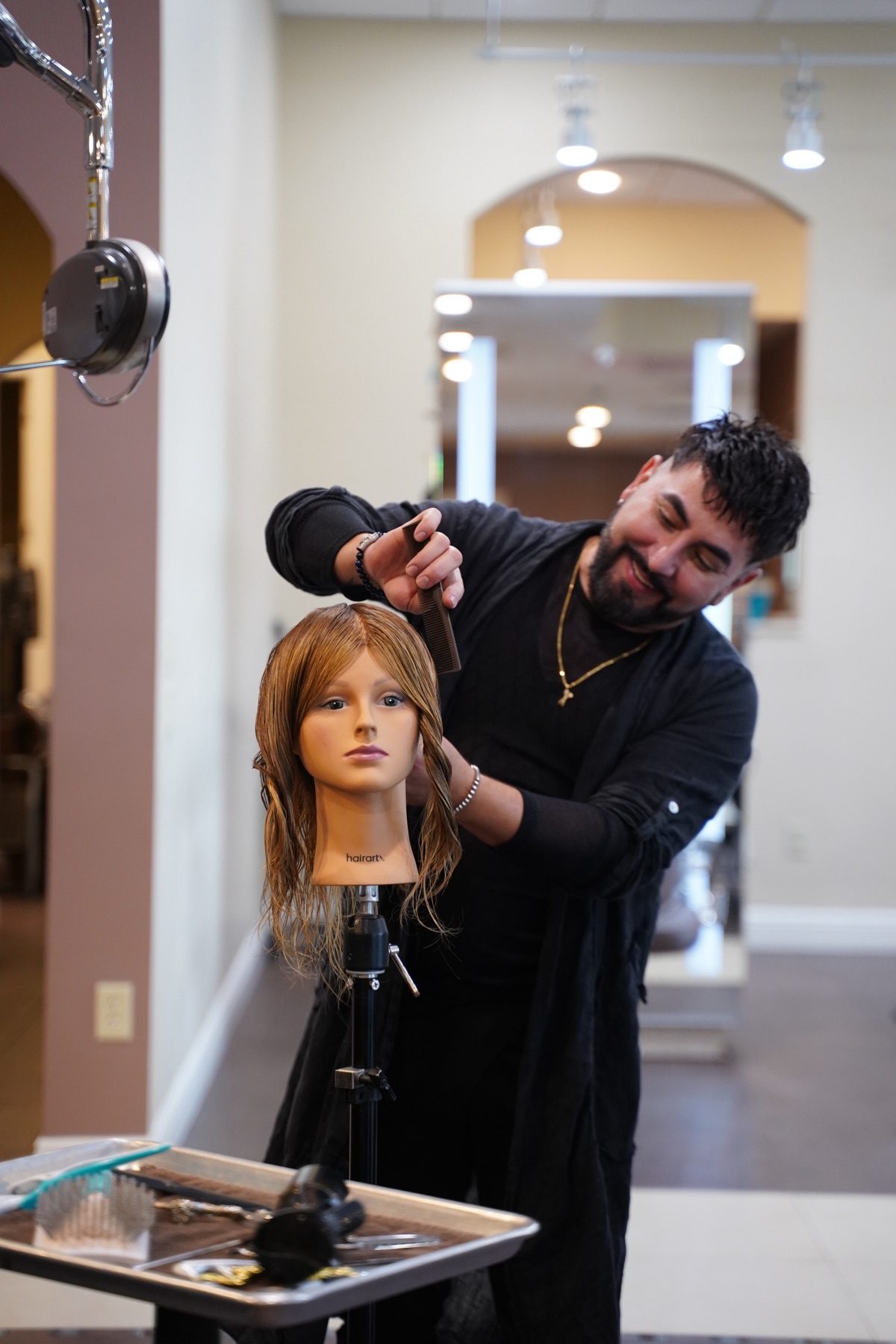 Ariel Cubas teaching a salon class, with stylists gathered around him